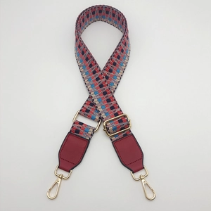 Detail of colorful geometric woven bag strap with gold lobster clasps and buckles