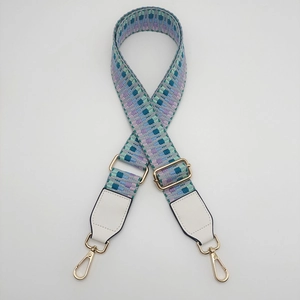 Macro view of adjustable woven bag strap with golden buckles and white leather ends