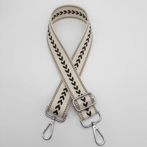 Detail view of adjustable beige nylon strap with black arrow pattern and silver hardware