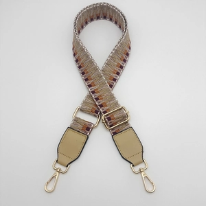 Close-up of adjustable woven shoulder strap with geometric wave pattern and gold metal hooks