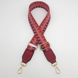 Close-up of red and pink jacquard woven strap with golden metal hardware and leather ends