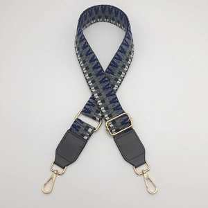 Detail of adjustable geometric blue woven strap with gold metal hooks and leather ends