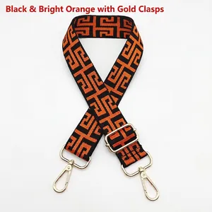 Detail of black and orange geometric canvas strap with golden metal lobster clasps