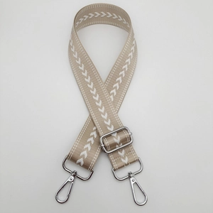 Detail of adjustable khaki nylon bag strap with white chevron embroidery and metal hooks