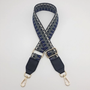 Detail showing the adjustable geometric woven shoulder strap with gold metal lobster clasps