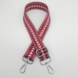 Close-up of adjustable burgundy nylon bag strap with white arrow pattern and silver hooks