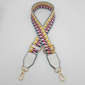 Detail view of colorful geometric woven bag strap with white leather and gold hooks