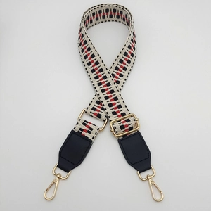 Detail of adjustable woven bag strap featuring red and black geometric tribal patterns