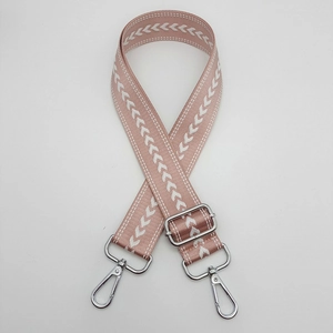 Detail of pink adjustable nylon bag strap with white arrow pattern and silver metal clasps