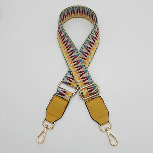 Detail of adjustable woven handbag strap with colorful geometric patterns and gold metal buckles