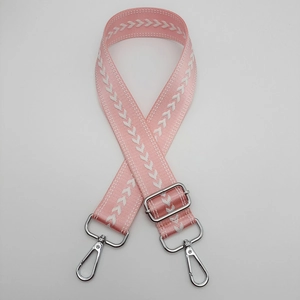 Detailed view of pink nylon bag strap with white arrow embroidery and silver metal hooks