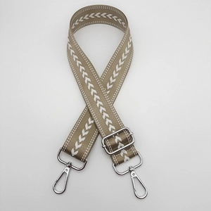 Close-up of adjustable khaki nylon strap with white arrow pattern and silver metal buckles