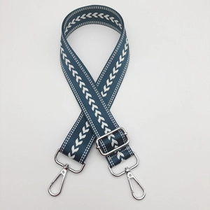Detail of adjustable nylon bag strap with teal base, white arrow pattern, and silver hooks