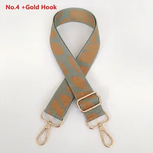 Detail of leaf pattern woven strap with golden swivel snap hooks and adjustable slider