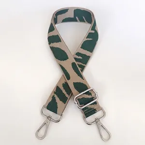 Close-up of wide green and beige woven strap with silver metal hooks and buckle