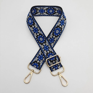 Detail of ethnic floral embroidered bag strap with golden metal hooks and adjustable slider