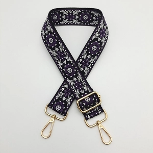 Detail of bohemian purple embroidered bag strap with golden metal hardware and floral pattern