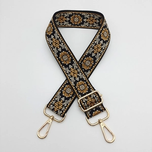 Close-up of woven ethnic bag strap with floral pattern and gold metal lobster clasps