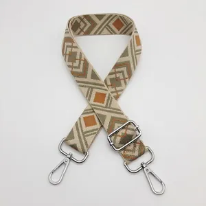 Close-up of geometric pattern on wide adjustable nylon bag strap with silver metal hooks