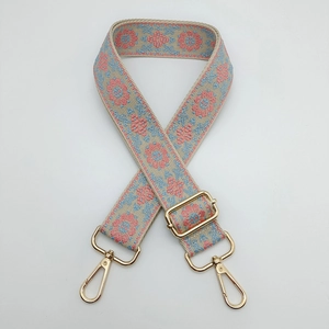 Detail of floral ethnic embroidery on beige guitar style strap with gold metal hooks