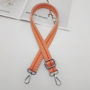 Close-up of orange and white herringbone woven canvas bag strap with silver metal hooks
