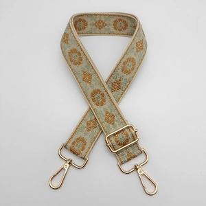 Detail of retro floral embroidery on wide adjustable woven strap with gold metal hooks