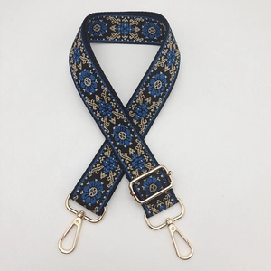 Close-up of ethnic embroidered bag strap with floral patterns and gold metal swivel hooks