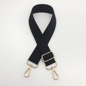Close-up of adjustable wide canvas bag strap with geometric patterns and gold buckles