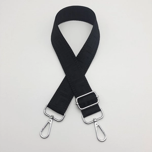 Detail of black woven canvas bag strap with geometric jacquard pattern and silver hooks