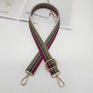 Close-up of adjustable striped canvas shoulder strap with luxury gold metal hooks