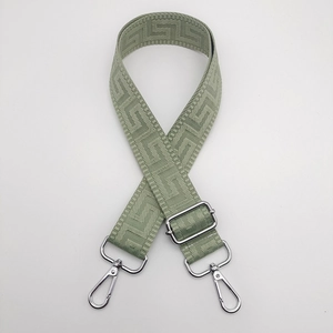 Detail of sage green nylon bag strap featuring geometric jacquard and silver hardware