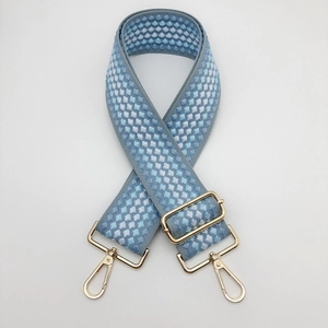 Dettaglio della tracolla in tela intrecciata geometrica blu e bianca con fibbie dorate