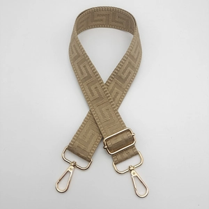 Detail view of khaki wide canvas strap with Greek key pattern and gold swivel hooks