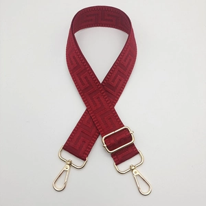 Detail of burgundy wide strap with Greek Key pattern and gold-tone lobster clasps