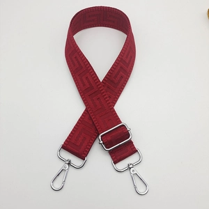 Close-up of red wide canvas shoulder strap with geometric pattern and silver metal clips