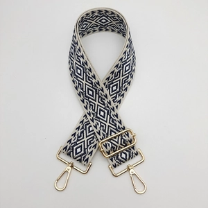 Close-up of adjustable navy and cream diamond pattern nylon strap with gold metal hooks