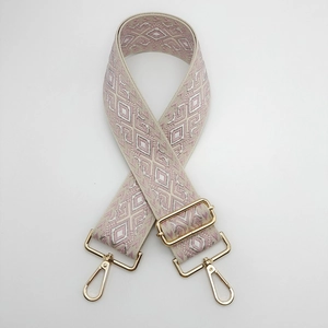 Detail of adjustable pink and beige diamond pattern jacquard canvas bag strap with gold metal hooks