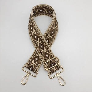 Detail view of adjustable nylon bag strap with geometric diamond embroidery and gold buckles
