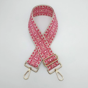 Macro shot of geometric weave purse strap with gold metal hooks and adjustable buckle