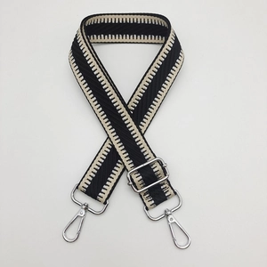 Détail d'une bandoulière tissée géométrique noir et blanc avec crochets métalliques