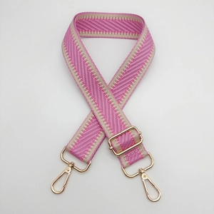 Détail de la bandoulière tissée rose et beige avec des crochets en métal doré brillant