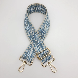 Close-up of adjustable woven purse strap with blue and beige diamond patterns and gold hooks