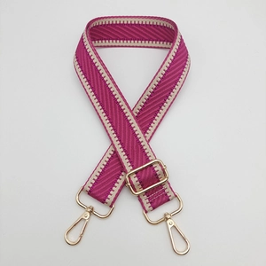 Détail de la bandoulière tressée magenta avec mousquetons dorés et boucle de réglage