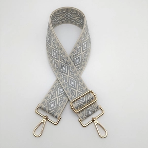 Detail of adjustable nylon strap with grey diamond pattern and gold metal lobster clasps