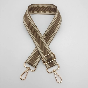 Détail de la bandoulière tissée réglable marron et beige avec des mousquetons dorés polis
