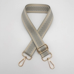 Détail de la bandoulière tissée gris argenté avec motif chevrons et fermoirs dorés
