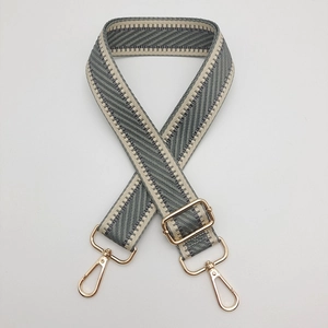 Détail de la bandoulière tissée à chevrons gris et beige avec mousquetons en métal doré