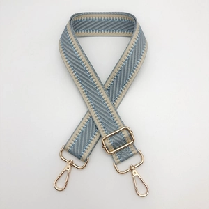 Détail d'une bandoulière tissée bleue et beige avec fermoirs métalliques dorés et mousquetons