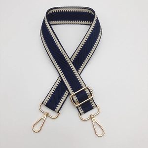 Détail de la bandoulière tissée bleu marine et beige avec mousquetons dorés polis