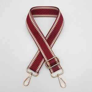 Détail de la bandoulière tissée bordeaux et beige avec crochets rotatifs dorés